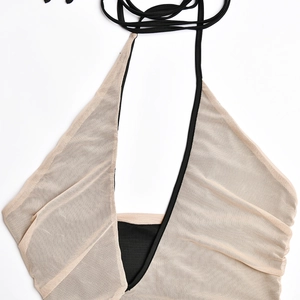 Détail du haut dos nu en maille beige et tissu noir avec lacets de fermeture