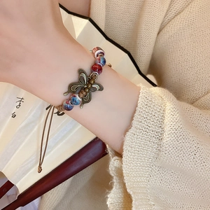 Detail of vintage butterfly charm on hand-woven rope bracelet with ceramic beads