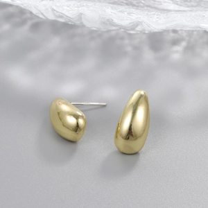Macro shot of minimalist gold teardrop earrings with high-polish metallic finish