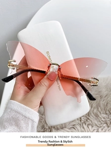 Detail of butterfly-shaped rimless sunglasses with pink gradient lenses and gold metal frame
