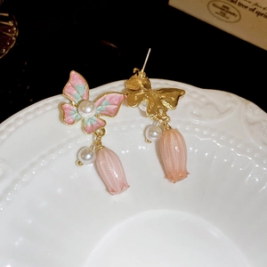 Détail de boucles d'oreilles papillon avec émail dégradé, perles et boutons floraux
