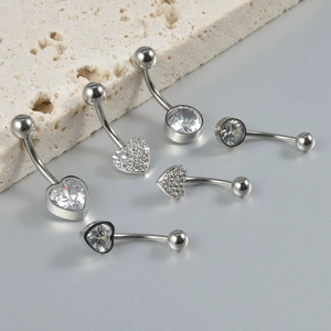 Close-up of heart and round shaped silver navel rings with cubic zirconia inlay