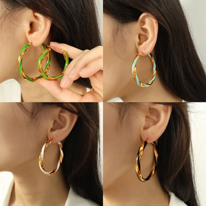 Golden twisted hoop earrings with colorful enamel details shown on a model