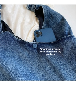 Detail of blue denim tote bag featuring an external pocket with a mobile phone inside