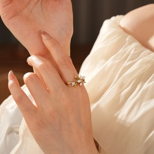 Dettaglio dell'anello a fiore placcato oro con smalto bianco e tocchi verdi al dito
