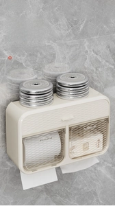 Detail of cream-white wall-mounted toilet tissue box with top storage and strong load capacity