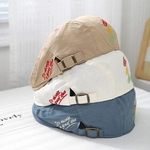 Close-up of three retro kids' beret hats with custom embroidery and metal buckles
