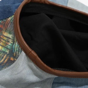 Detailed view of plaid beret showing blue denim, floral patchwork and leather trim