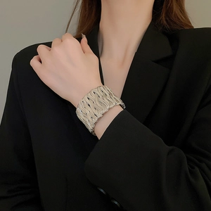 Close-up of woven silver twisted cuff bracelet on wrist for a minimalist luxury look