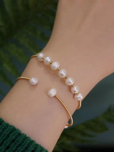 Detail of vintage gold pearl bracelet set with handmade wire wrap on a green sweater