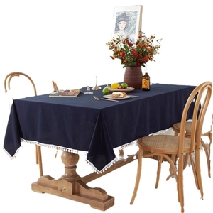 Modern solid blue cotton tablecloth with white tassel edges on a wooden table