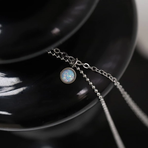 Close-up of double-layer titanium steel chain with blue opal round pendant detail