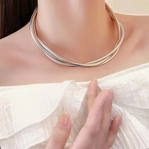 Close-up of triple-strand bicolor metal snake chain necklace on model neck