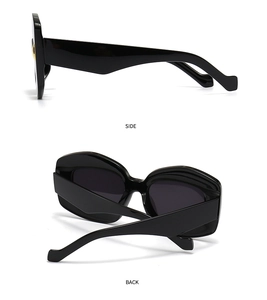 Detail view showing side and back of black oversized irregular sunglasses with gold accents