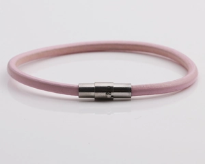Dettaglio di un bracciale in pelle rosa con chiusura magnetica argento su fondo grigio