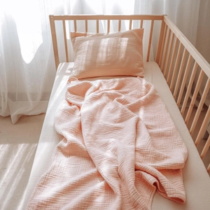 Detailed view of pink muslin baby bedding set with soft textured blanket and pillow