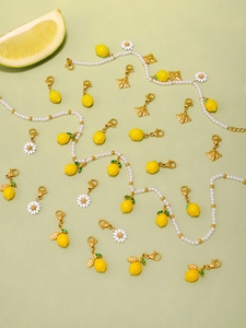 Dettaglio dei ciondoli a limone e margherita su una collana estiva di perle lucide