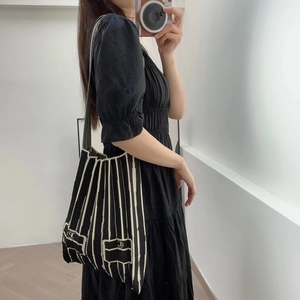 Close-up of black and white pleated knit tote bag with striped texture on female model