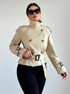 Detail of khaki short trench coat featuring double-breasted buttons and adjustable waist belt