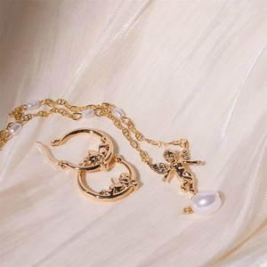 Elegant gold Cupid angel pendant necklace and earrings set with pearls on satin cloth