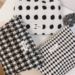 Détail de trousses de maquillage en tweed et pied-de-poule avec étiquette et chouchou