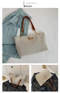 Detail of vintage beige canvas tote bag with brown leather handles and golden deer charm