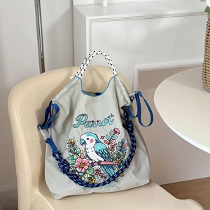Detailed view of parrot embroidery and floral patterns on a nylon drawstring tote bag