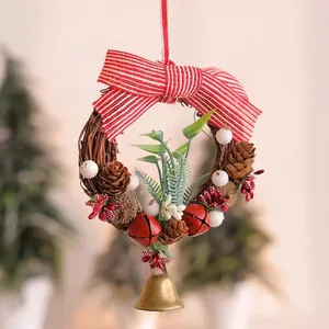 Détail d'une couronne de Noël de 14cm avec pommes de pin, cloches et nœud rayé rouge