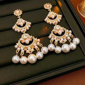 Detailed macro view of fan-shaped fringe earrings with pearls and pink crystals