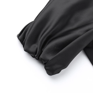 Detailed view of black satin fabric with elegant pleated texture and ruffled hemline