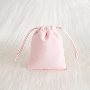 Pochette en velours rose à cordon pour bijoux sur fond de peluche blanche douce