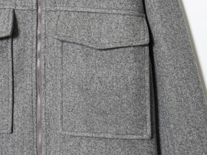 Détail macro de la veste en laine montrant la fermeture éclair et les coutures de poche