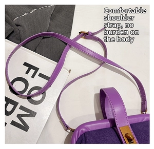 Detail of purple faux suede handbag showing gold twist lock and smooth leather trim