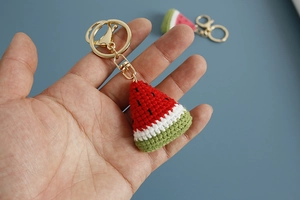 Handmade crochet watermelon slice keychain held in hand with gold metal ring detail