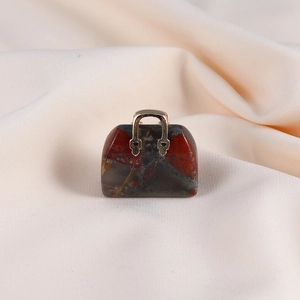 Detailed view of mini handbag pendant with red natural stone texture and gold handle