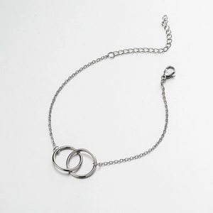 Detailed view of silver interlocking double ring pendants on a fine chain bracelet
