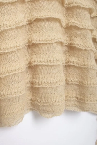 Detail of tiered ruffles on light beige mohair blend knitwear with wave texture