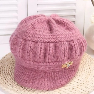 Detailed close-up of pink knit visor hat with warm fleece lining and gold metal accent