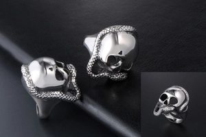 Detail of silver stainless steel skull and snake ring on black leather texture background