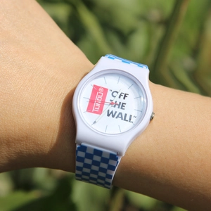 White minimalist wristwatch with blue checkerboard silicone strap worn on wrist