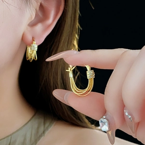Gros plan détaillé de boucles d'oreilles multicouches plaquées or avec zircons brillants