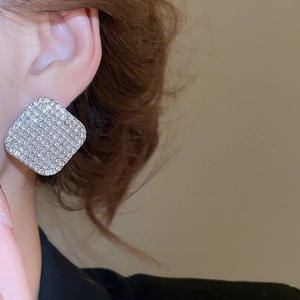 Primo piano di una donna con un orecchino a bottone quadrato in argento con cristalli