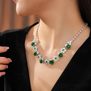 Detailed view of luxury cubic zirconia flower necklace with green gems on a model