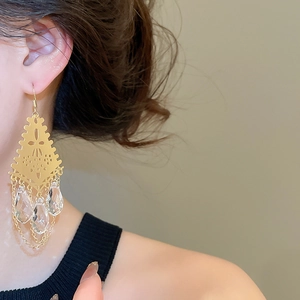 Detail of gold hollow geometric tassel earrings with clear crystal drop on model