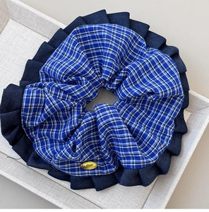 Close-up of blue plaid scrunchie with denim ruffle and min metal charm detail
