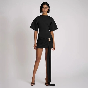 Detail of black dress featuring ruffled waist with golden buckle and flowing fabric sash