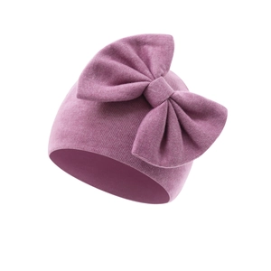 Close-up of baby knit hat in plum pink with a large decorative bow and soft texture