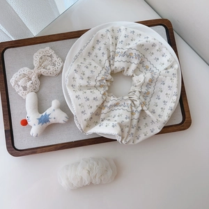 Close-up of beige floral cotton scrunchies displayed on a white plate with aesthetic decor