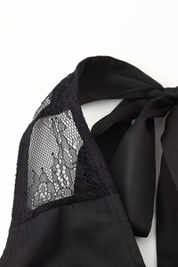 Dettaglio dell'abito nero con cuciture in pizzo e grande fiocco decorativo sulla schiena