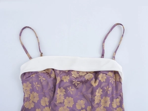 Close-up of purple jacquard dress featuring golden floral pattern and white trim
